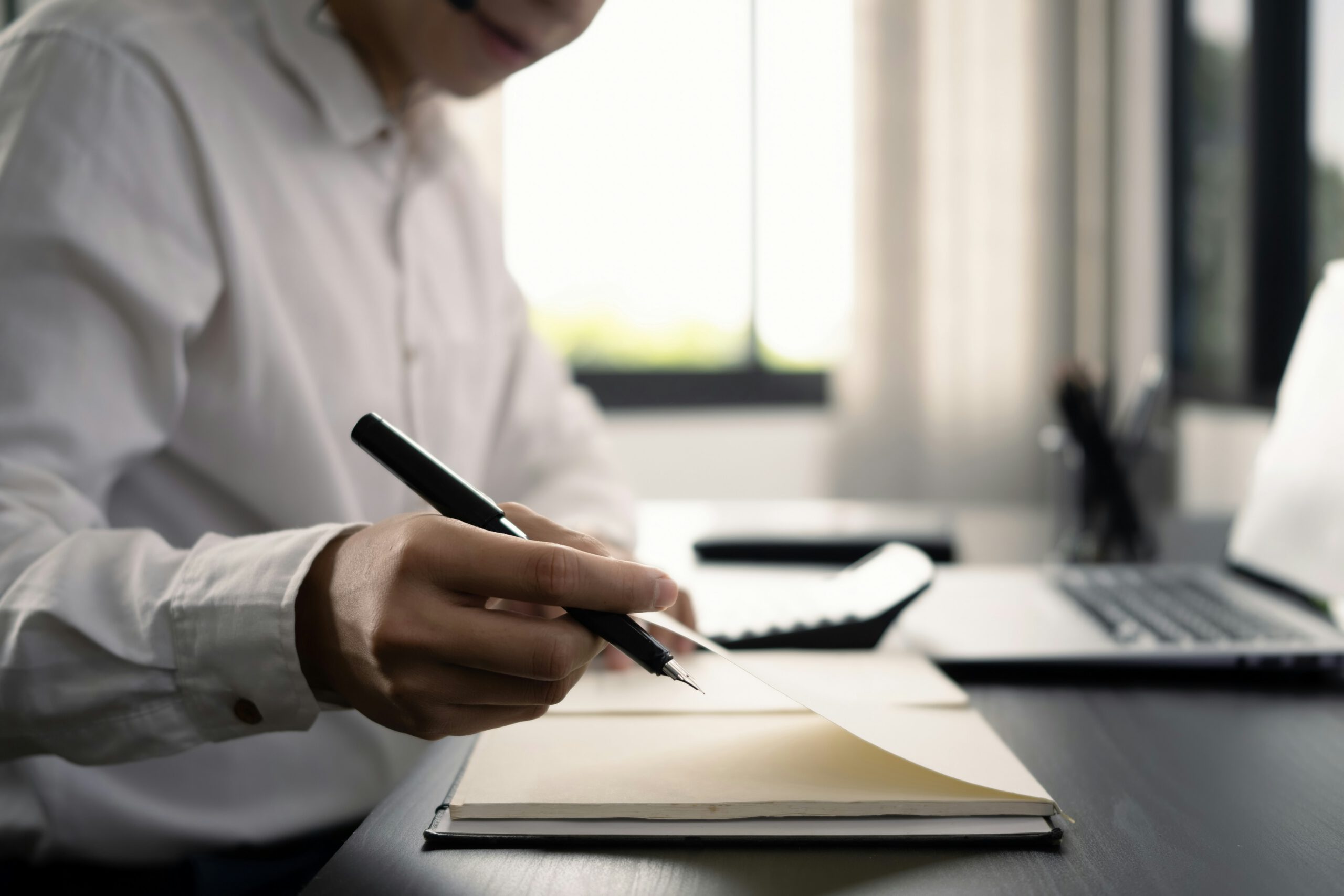 Mano escribiendo notas durante una sesión de consultoría tecnológica y estrategia empresarial
